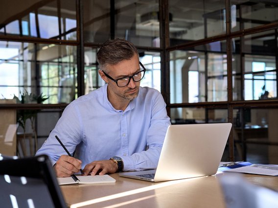 Kooperation mit TÜV NORD: Personenzertifikate in Ihrem Unternehmen Ein Mann macht sich Notizen vor einem Laptop