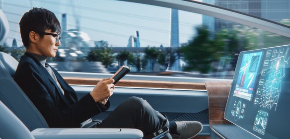 Mann sitzt in einem automatisierten Fahrzeug