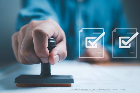 Hand stempelt Dokument, daneben schwebende Symbole von Dokumenten mit Häkchen.