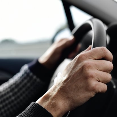 Automotive Titelbild Mann mit beiden Händen am Lenkrad eines Autos.