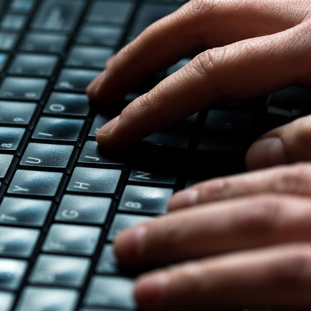 Zwei Hände tippen auf PC-Tastatur. Großaufnahme zweier Hände, die auf einer schwarzen PC-Tastatur tippen.
