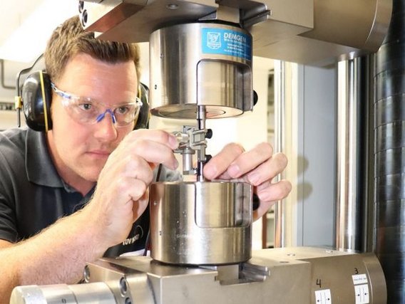 Quality Control in 3d printing Ein Prüftechniker richtet ein Prüfstück in einer Zugprüfmaschine ein, um Materialeigenschaften zu testen.
