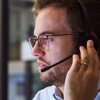 Mann mit Headset Ein Mann blickt zur Seite während er an das Headset fass, mit dem er gerade telefoniert.