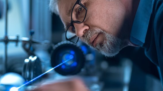 TÜV NORD Produktzertifizierung Ein Mann prüft einen Laser.