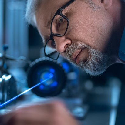 TÜV NORD Produktzertifizierung Mann prüft Produkt mit einem Laser.