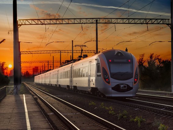 Zugfahrt bei Sonnenuntergang auf der Bahnstrecke Moderner Zug bei Sonnenuntergang auf einer Bahnstrecke