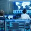 IT-Spezialisten überwachen globale Netzwerksysteme in einem Kontrollzentrum mit mehreren Bildschirmen.