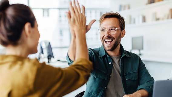 Zwei Personen geben sich ein High-Five nach Abschluss einer Qualifikation mit Zertifikat durch den TÜV NORD.