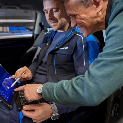 Fahrzeugprüfung an der TÜV NORD Station mit Laptop-Unterstützung Prüfingenieur und Kunde bei der Fahrzeugprüfung mit Laptop