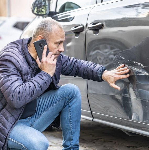 TÜV NORD damage assessment Man sits by the car with scratches