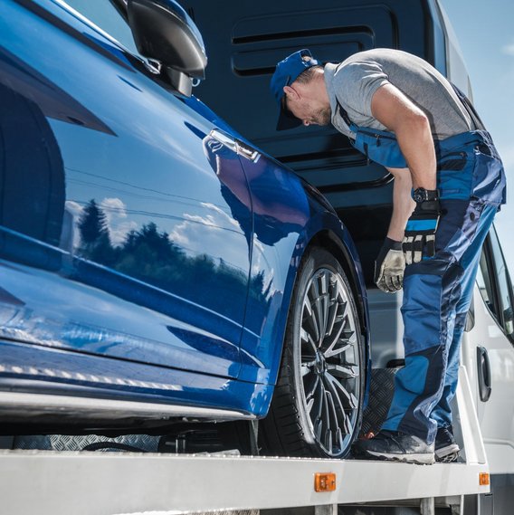 Fahrzeuginspektion auf Abschleppwagen Mitarbeitr inspiziert Fahrzeug auf Abschleppwagen