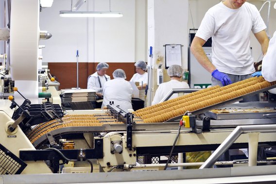 Zertifizierungen der Lebensmittelproduktion Anlage zur Keksproduktion mit Mitarbeitenden in Schutzkleidung