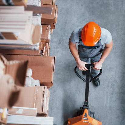 Top view eines Arbeiters im Warenhaus mit Palletenhubwagen Top view eines Arbeiters im Warenhaus mit Palletenhubwagen
