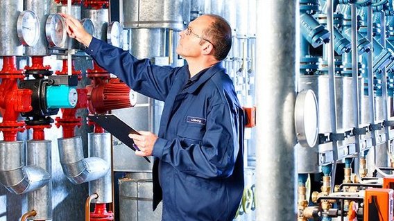 TUEV_NORD_Energiemanagementsystem TÜV NORD Experte überprüft Messgeräte und Ventile in einer Industrieanlage.