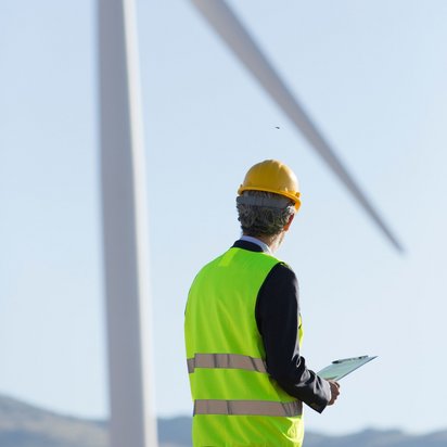 Ein Ingenieur beobachtet eine Windkraftanlage mit der Ökostrom produziert wird. Ein Ingenieur beobachtet eine Windkraftanlage mit der Ökostrom produziert wird.