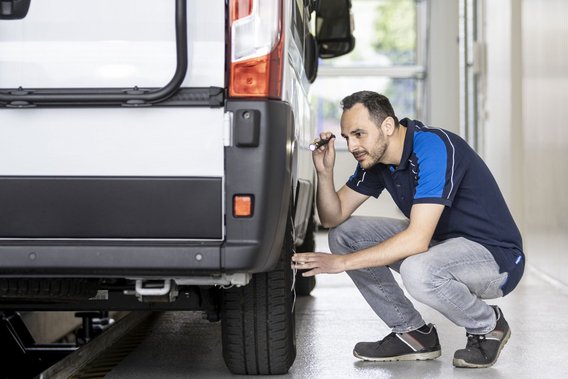 Reifeninspektion eines Wohnmobils an der TÜV NORD Station Prüfingenieur inspiziert die Reifen eines Wohnmobils an einer TÜV NORD Station