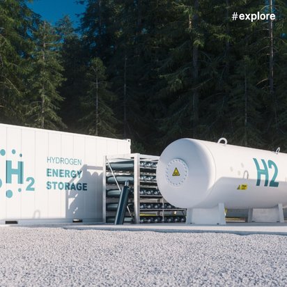 Eine Wasserstoff-Energiespeicheranlage mit weißen H2-Tanks und einem Container für "Hydrogen Energy Storage" in einer Waldumgebung mit hohen Nadelbäumen.