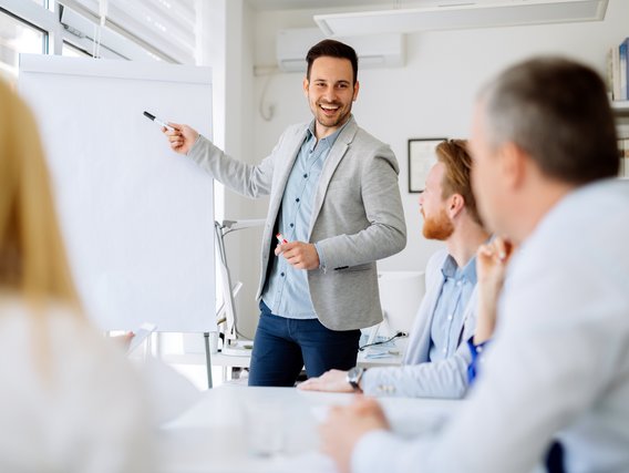 Training für Einsatzkräfte im sicherheitskritischen Umfeld Mann präsentiert vor einer Gruppe in einem hellen Besprechungsraum an einem Flipchart