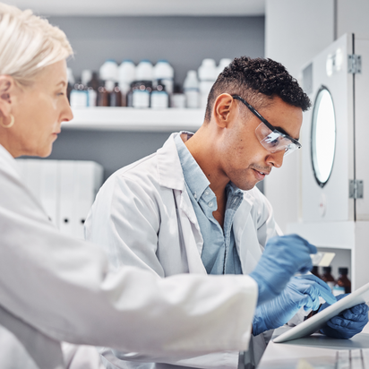 Ein Wissenschaftsteam arbeitet gemeinsam in einem Labor, betrachtet Daten auf einem Tablet Ein Wissenschaftsteam arbeitet gemeinsam in einem Labor, betrachtet Daten auf einem Tablet