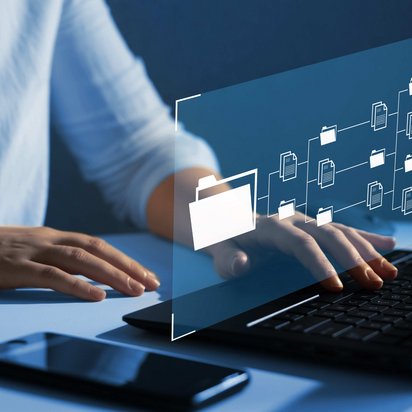 Person tippt auf Laptop mit schwebendem Interface aus Ordner- und Dokumentensymbolen.