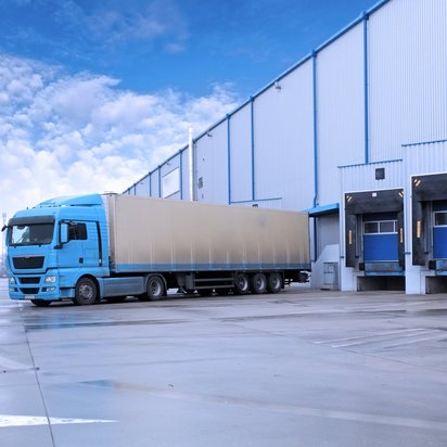 LKW verlässt eine Beladungsstation Symbolbild Logistik - LKW vor eine Reihe von Verladungsbuchten