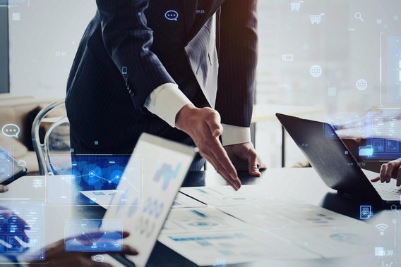 Geschäftspersonen in Besprechung mit Laptops und digitalen Datenvisualisierungen.