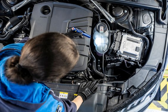 Motorinspektion durch Prüfingenieurin an der TÜV NORD Station Prüfingenieurin bei der Motorinspektion eines Fahrzeugs an der TÜV NORD Station